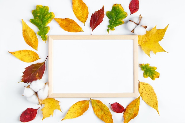 Empty frame mock up on white background and yellow fallen leaves Hello autumn concept