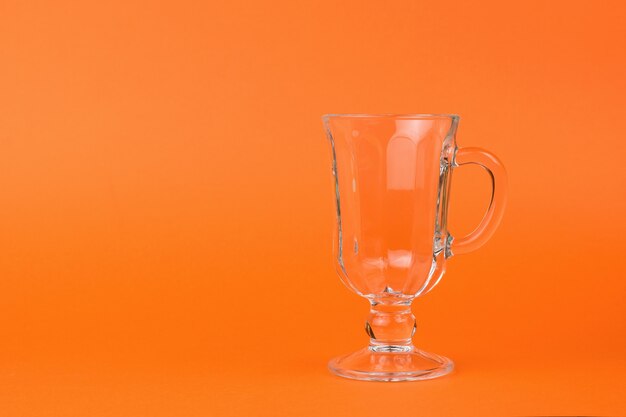 An empty glass coffee glass on an orange background.