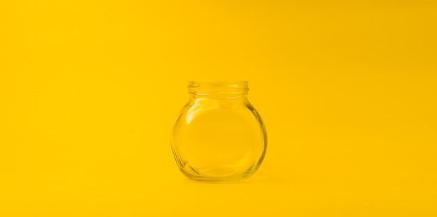 Empty glass jar on a yellow background with free space