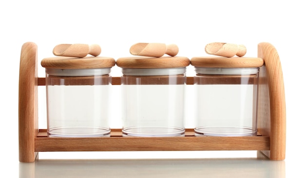 Empty glass jars for spices with spoons on wooden shelf isolated on white