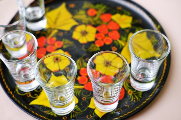 Empty glasses for alcohol stand on a tray painted in the old Russian style Shots are ready to meet guests