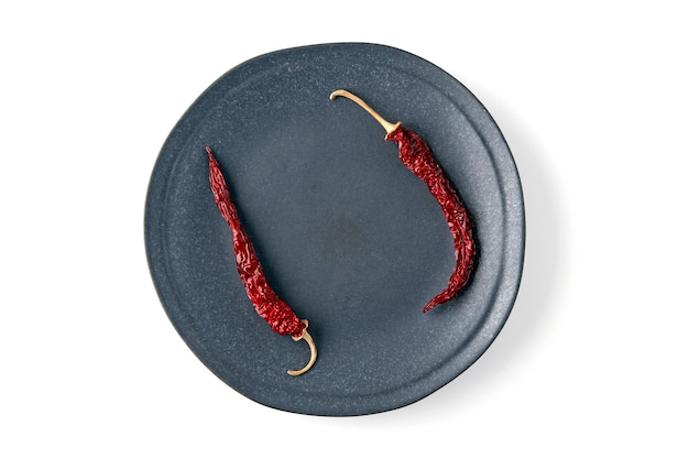 Empty gray ceramic plate with dried hot peppers isolated on white background Top view with copy space