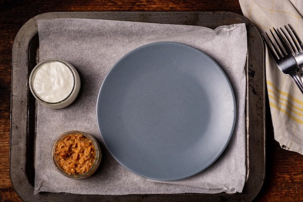 An empty gray plate and ketchup with mayonnaise next to it Preparing for serving