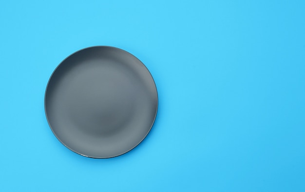 Photo empty gray round ceramic plate on a blue