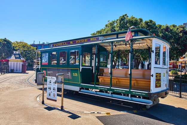 Empty green tourist streetcar trolley attraction at end of path with rotating circular platform