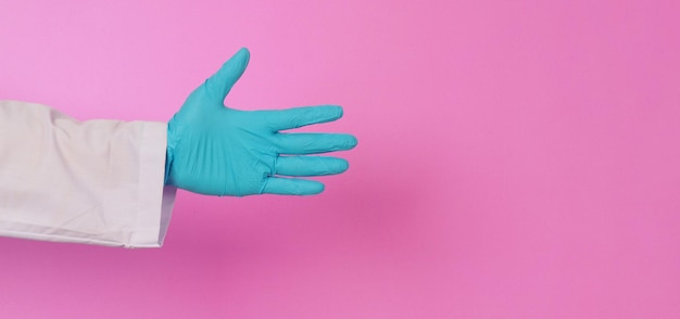 Empty hand Doctor hands wear blue latex glove on pink backgroundHe wear long sleeve gown