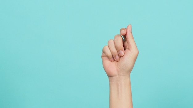 Empty hand holding nothing on light blue background.