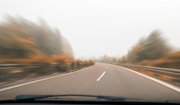 empty highway with motion blur at autumn, view from a car windshield, copyspace for your individual text.