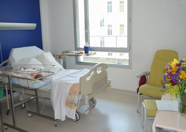 Empty hospital room with a bed for patient and newborn baby near the bed