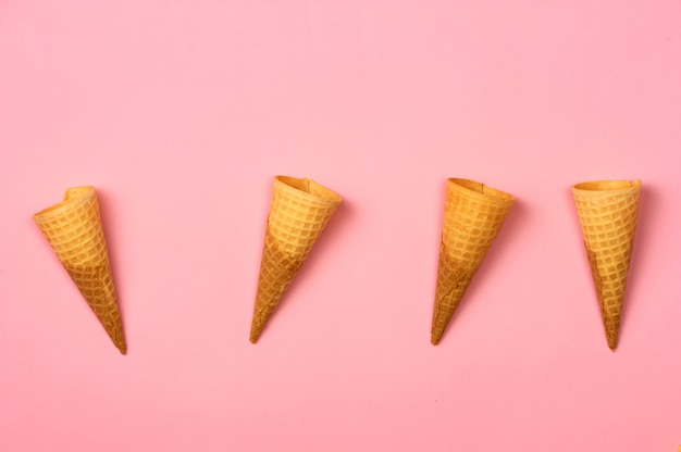 Empty ice cream cornet on pink background. Flat lay style.