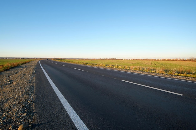 Empty intercity road with asphalt surface and white markings in evening