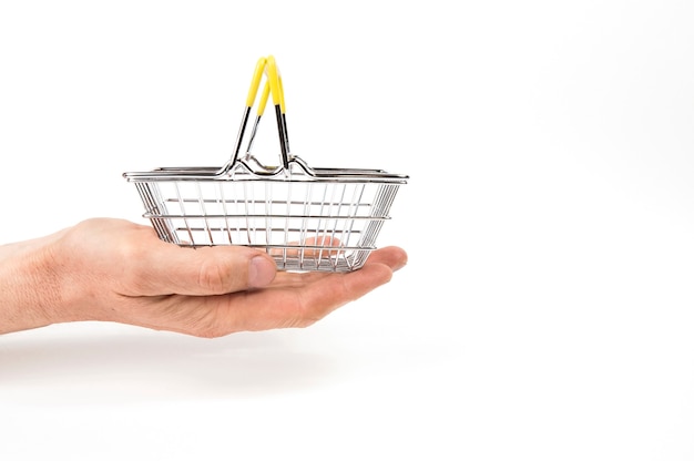 Empty iron shopping basket on the palm of a hand on a white