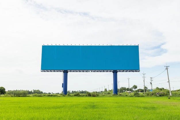 Empty large white advertising billboard in green rice field