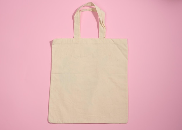 Empty linen eco friendly beige canvas tote bag for branding on a pink background Clear reusable bag for groceries mock up Flat lay