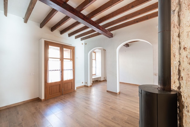 Empty living room of a town house with wooden beams, wooden floors and a stone wall