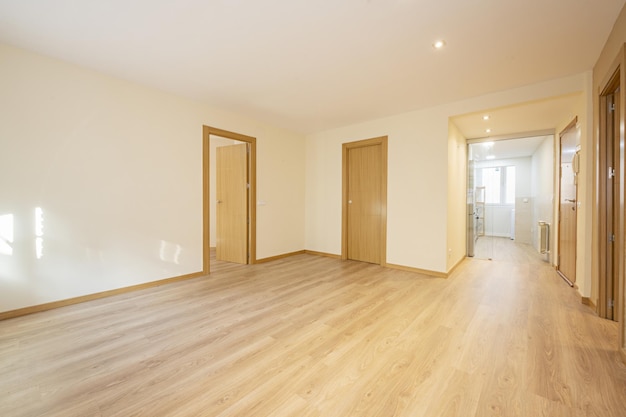 Photo empty living room with floating oak flooring access doors to other rooms in oak wood white painted walls and a separate kitchen with a glass partition with a door