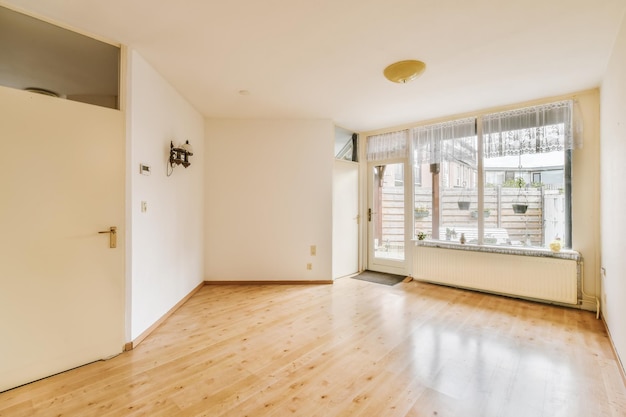 Photo an empty living room with wood flooring and large sliding glass door leading out to the balcony area