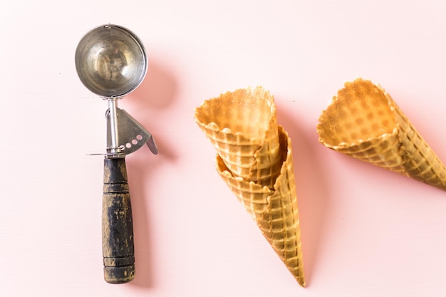 Empty metal ice cream scoop on pink background.