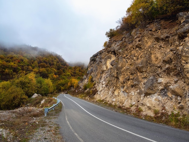 Empty morning highway through the pass in thick fog Beautiful asphalt freeway motorway highway through of caucasian landscape mountains hills at cold weather in mid october Ingushetia