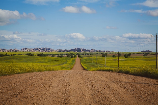 Empty muddy road with a green field on both sides on the countryside area