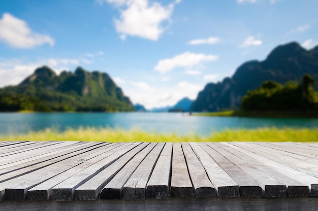 Empty old wooden table in front of blurred background of the lake mountain blue sky among bright sunlight on a clear day Can be used for display or montage for show your products