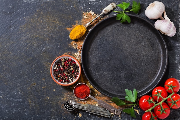 Empty pan with various products for cooking on dark background, top view