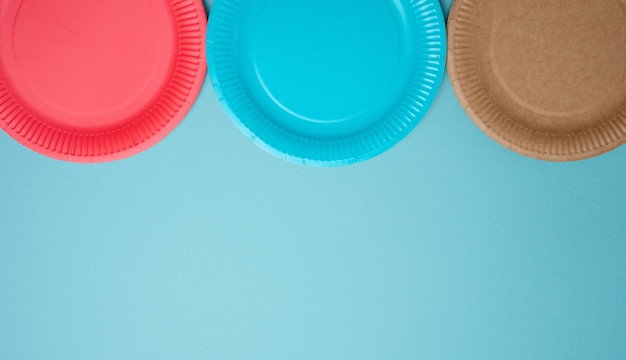 Empty paper disposable plates on a blue background top view