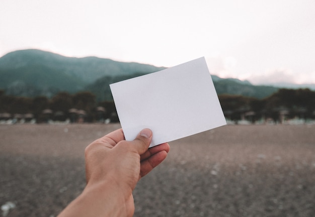 Empty paper note in hand at amazing landscape background. Travel and Vacation concept.