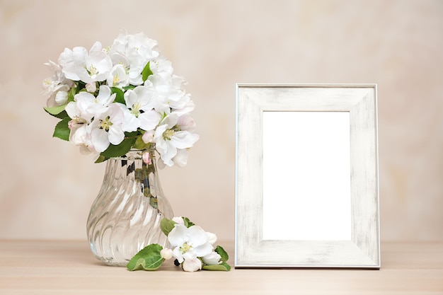 Empty photo frame and vase of flowers on the table