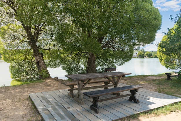 Photo empty picnic bench by the roadside next to the pond. tourism concept