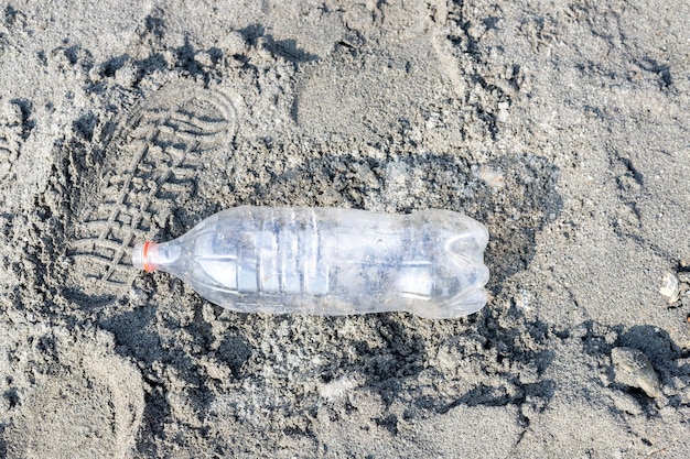 Empty plastic bottle trash laying on a sandy beach Plastic pollution concept