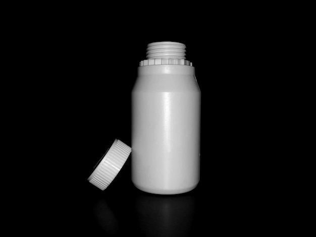 The empty plastic white bottle is on a dark background.