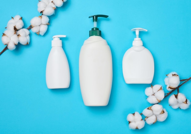 Empty plastic white bottles for cosmetics and other liquid substances on a blue background