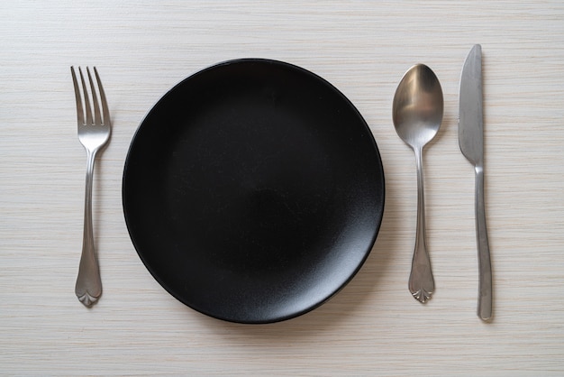 empty plate or dish with knife, fork and spoon on wood surface