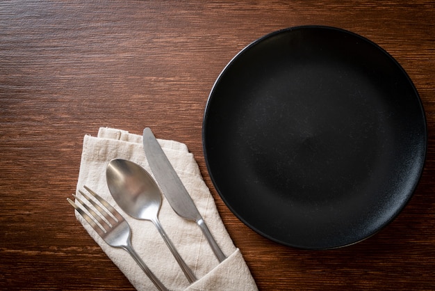 empty plate or dish with knife, fork and spoon on wood table