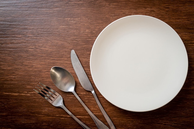 empty plate or dish with knife, fork and spoon on wood tile background