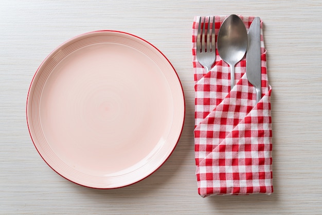 empty plate or dish with knife, fork and spoon on wood tile