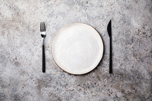 Empty plate  fork and knife on Gray Background