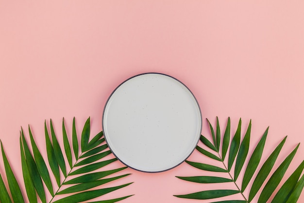 Empty plate with green tropical leaves