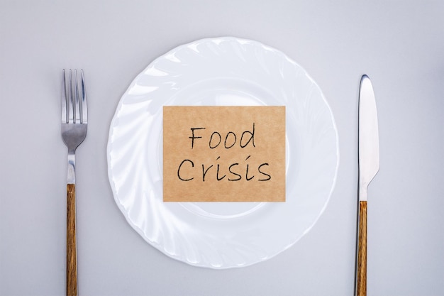 Empty plate with poster of food crisis Rising food cost