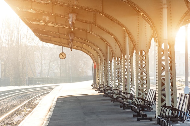 Empty platform with clock at railway station sunny day