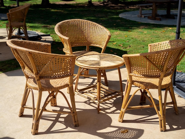 Empty rattan furniture outdoor garden weave table set with round table and three chairs on the green concrete floor in the green yard simple design