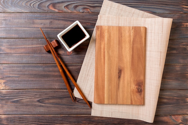 Empty rectangular wooden plate for sushi with sauce and chopsticks on wooden table