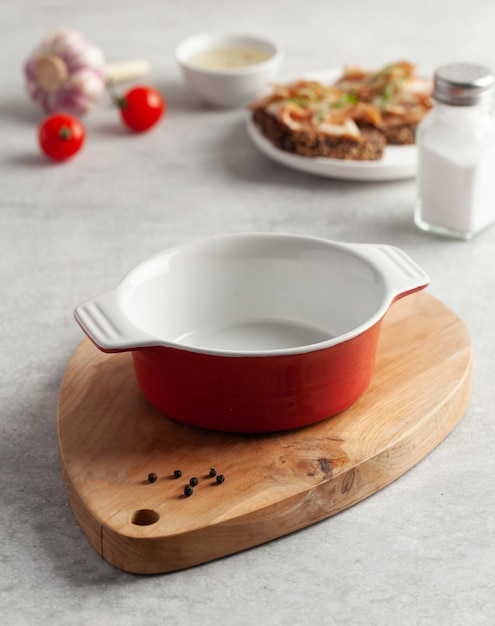 An empty red bowl on a wooden chopping board for soup slices of bread with salted pork bacon or lard