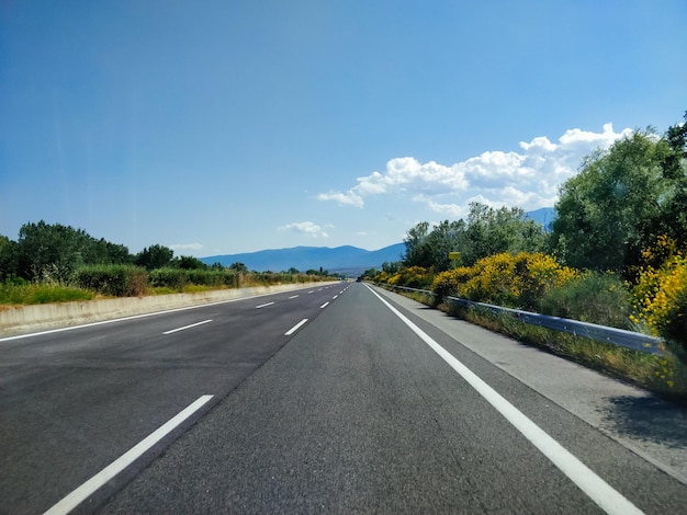 Empty road along trees and against sky