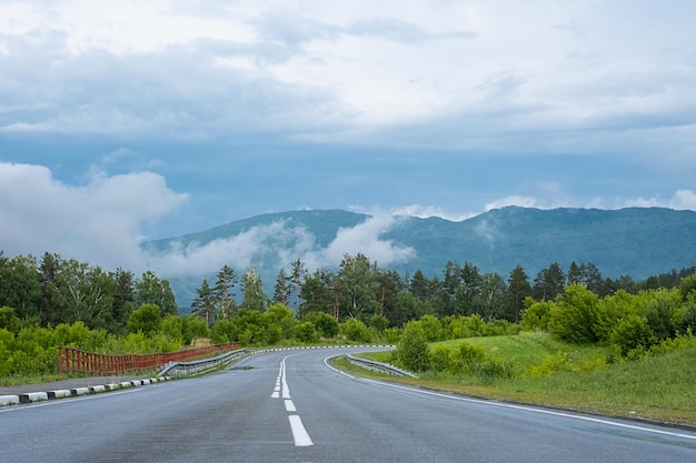 Empty road Speedway without cars in mountains amid pine forests Adventure or road trip background