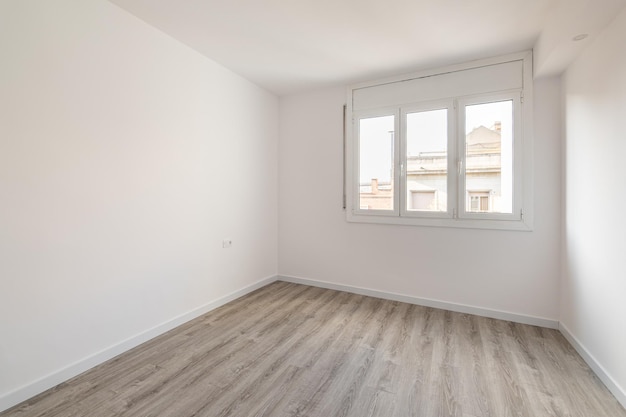 Empty room with laminate flooring newly painted white walls and bright window repair and