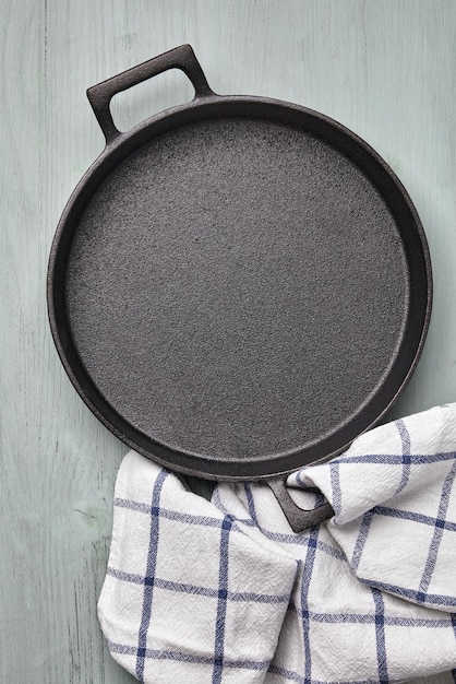 Empty round cast iron pan tea towel on a light blue wooden table Mockup for laying out food