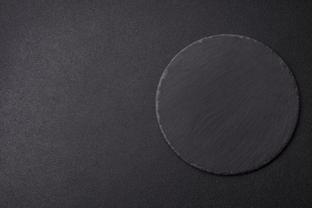 Photo empty round slate plate for template on the black background