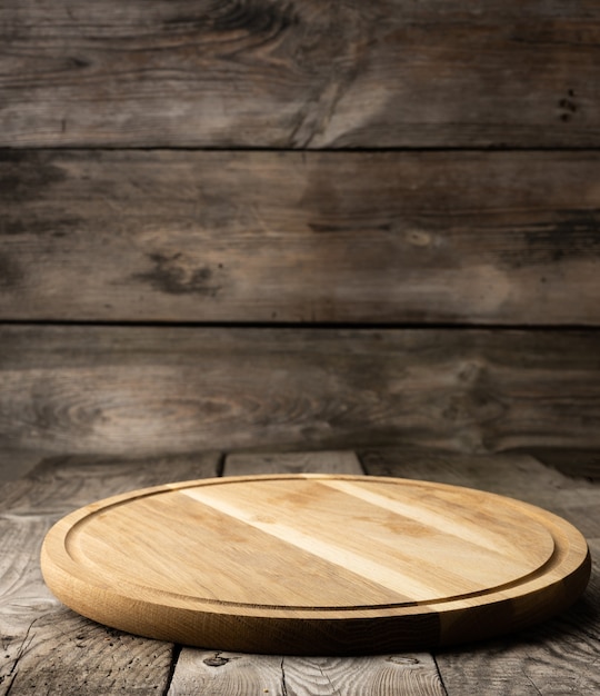 Empty round wooden cutting kitchen board on wooden surface, pizza board